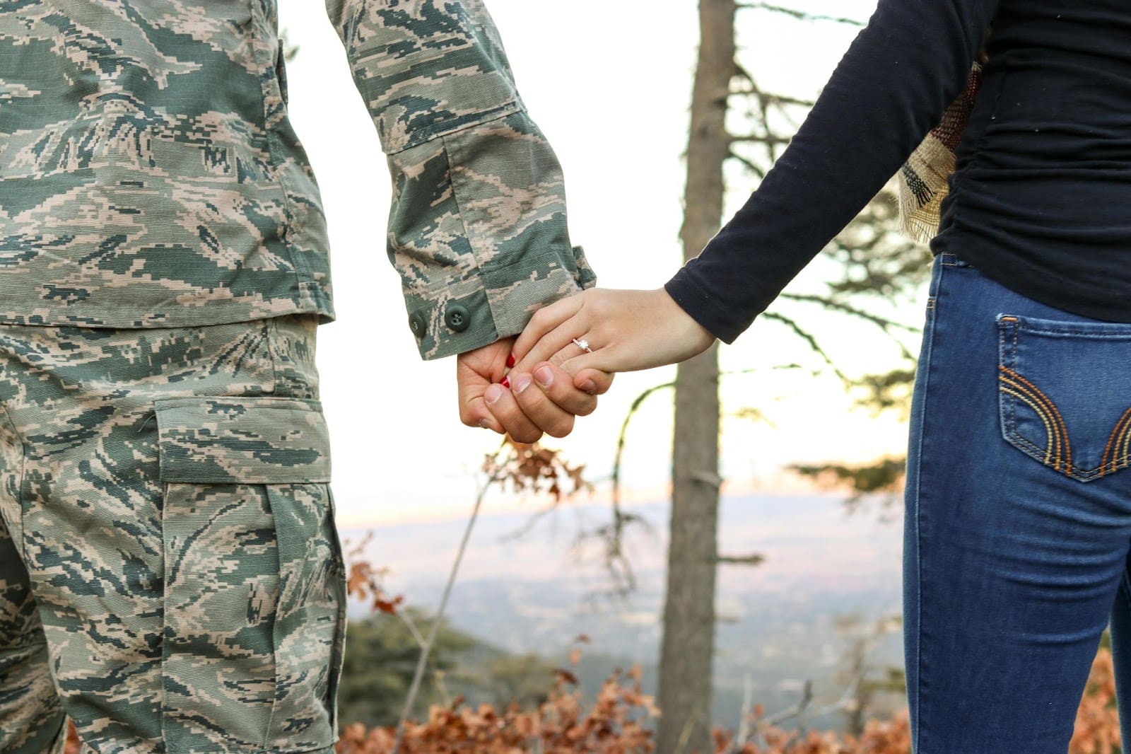 Military couple holding hands on a mountainside. | New Direction Family Law