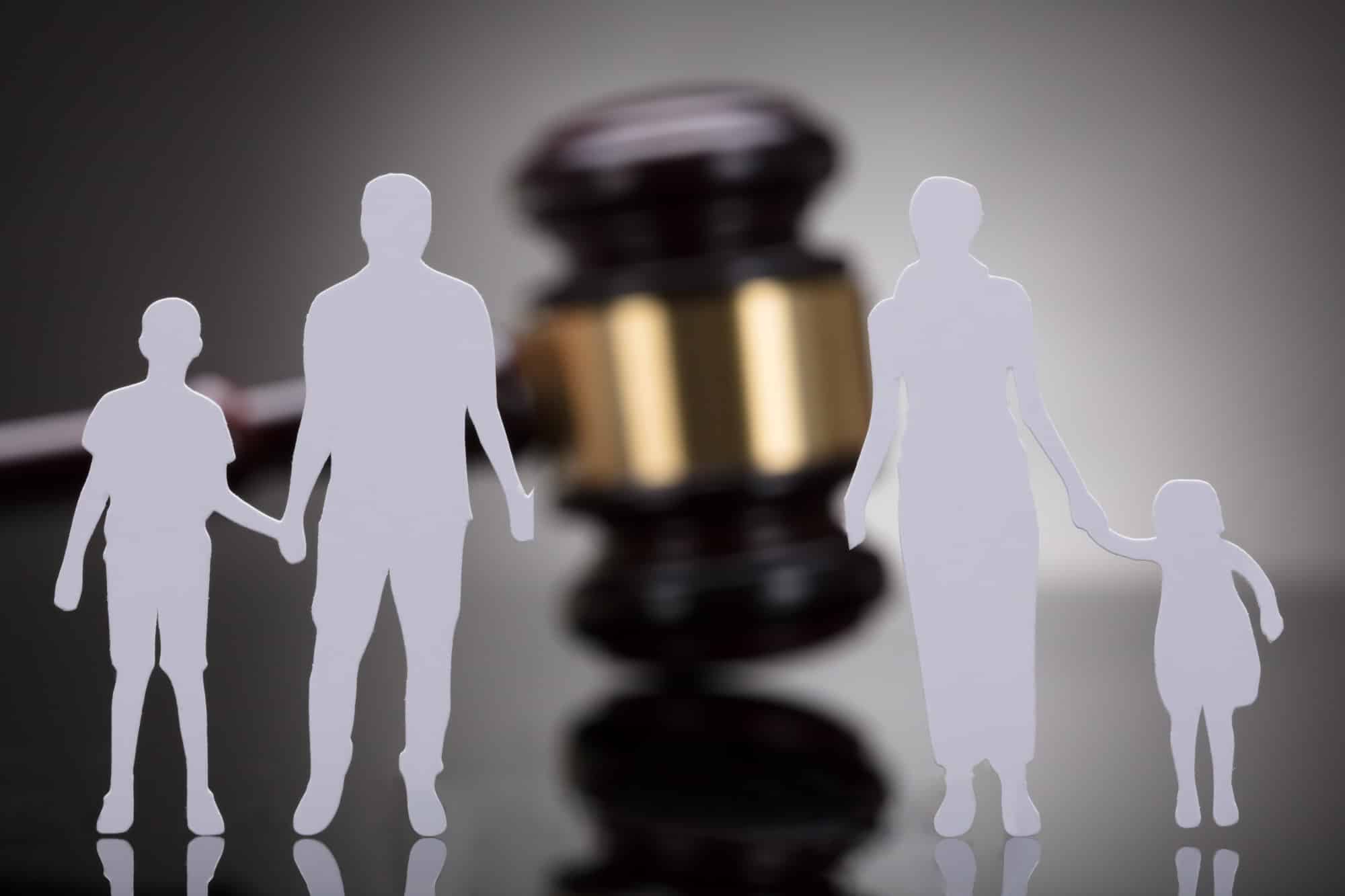 Separation of family figure cut away from gavel on grey background | New Direction Family Law