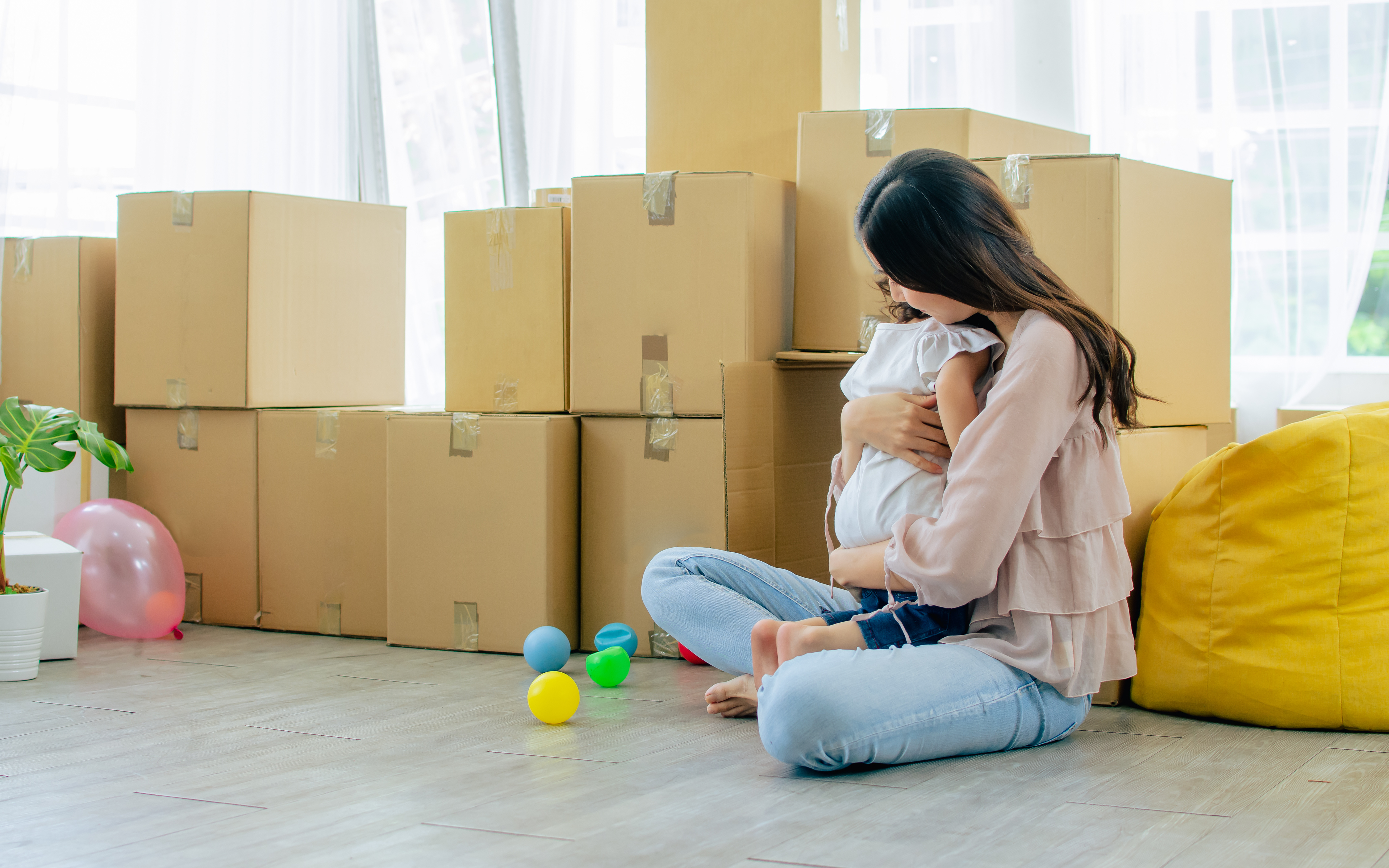 Woman hugging a child amidst moving boxes. | New Direction Family Law