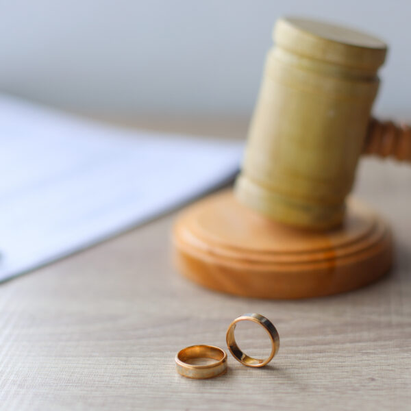 Gavel and wedding rings on a table with papers | New Direction Family Law