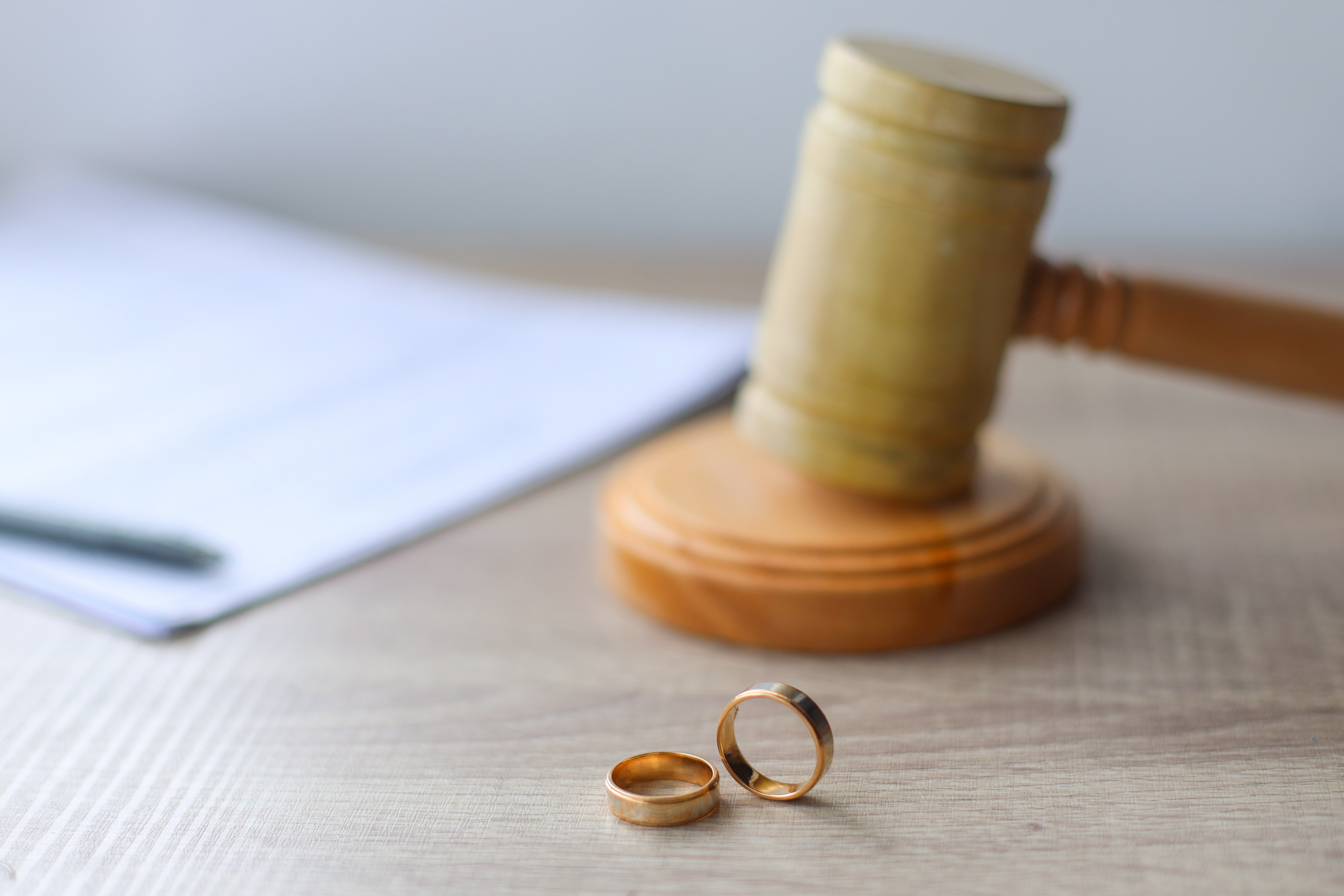 Gavel and wedding rings on a table with papers | New Direction Family Law