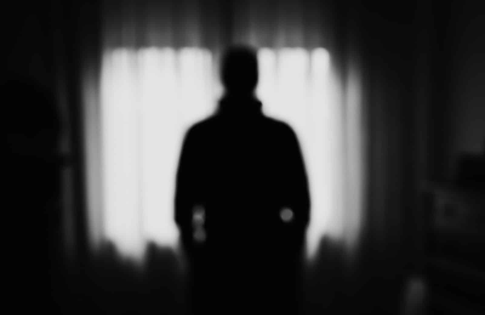 Shadowy black and white figure standing in a room | New Direction Family Law