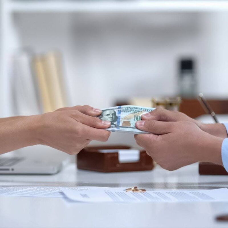 A man and woman both holding onto a stack of money bills.