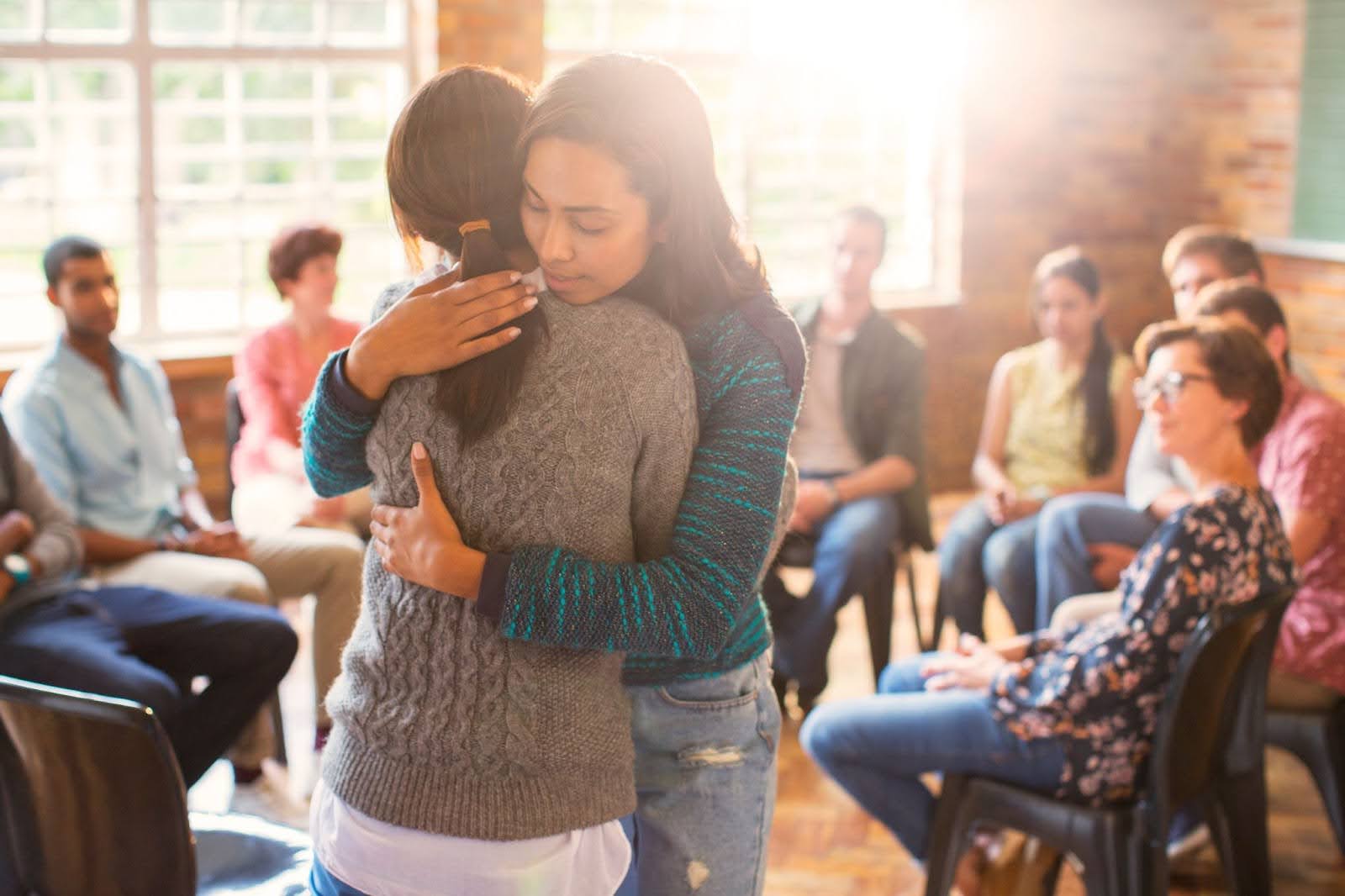 Two women hugging around the support group circle. | New Direction Family Law