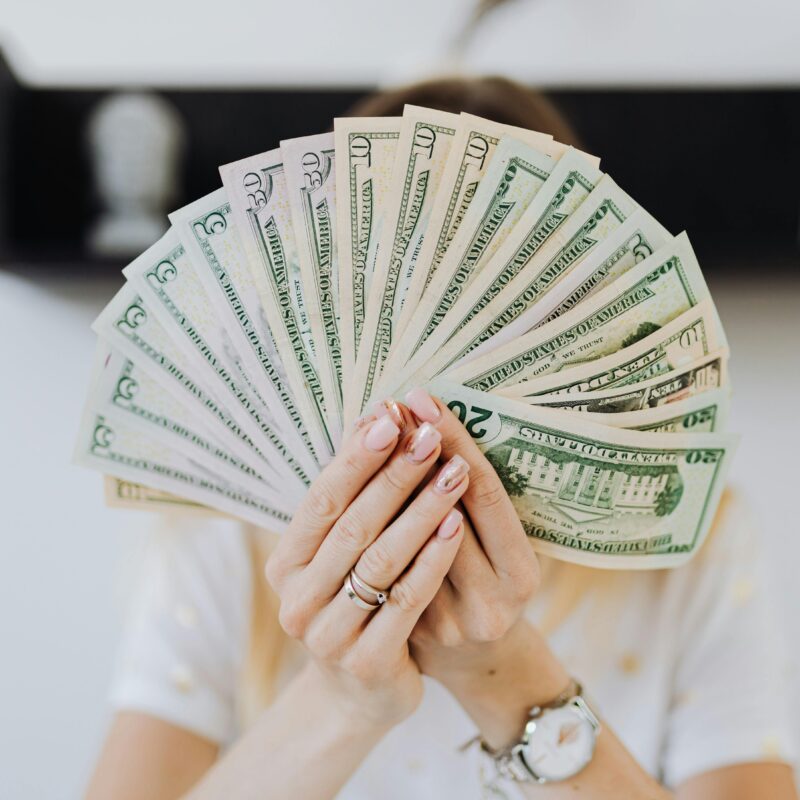Money bills fanning in front of woman's face.