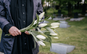 man holding flowers at gravesite