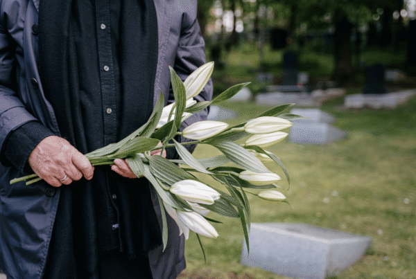 man holding flowers at gravesite